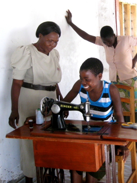 Abusa Nyirongo teaching the girls to use a treadle sewing machine