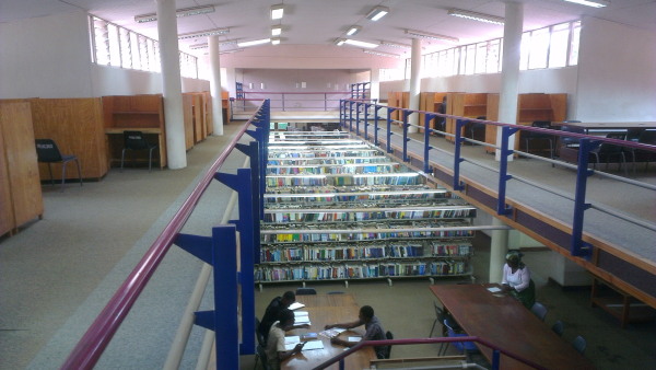 Some students studying at tables near the main stacks of the the library